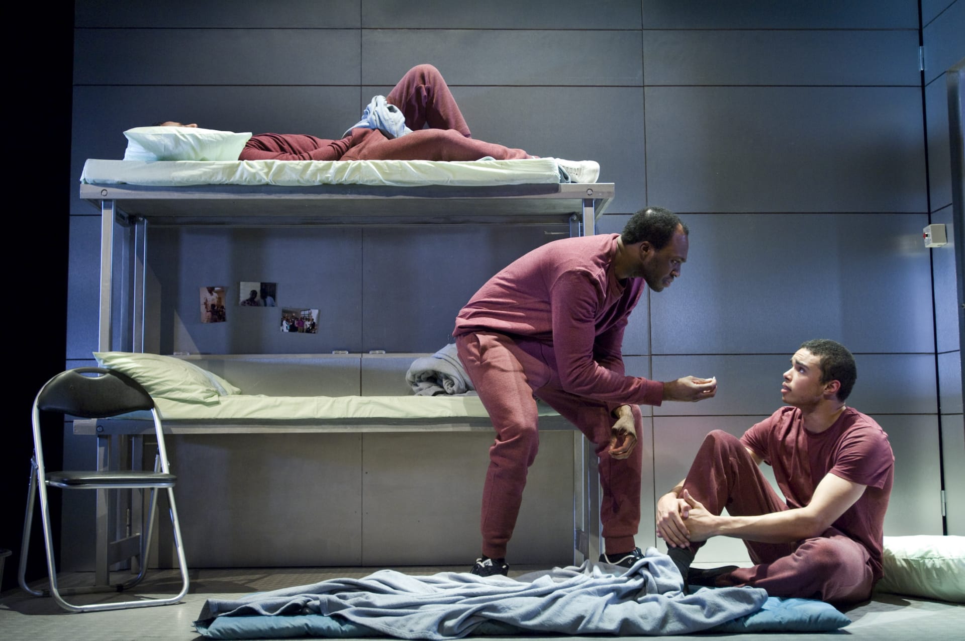 A prisoner, speaking to another prisoner who is sat on the floor.