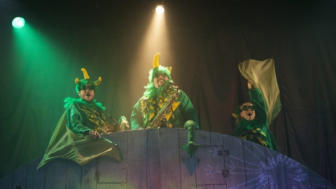 Three Actors with green and yellow costumes, with feathers, horns and wings.