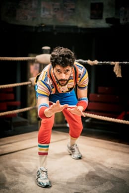 A wrestler bent over in the corner of a ring ready to attack