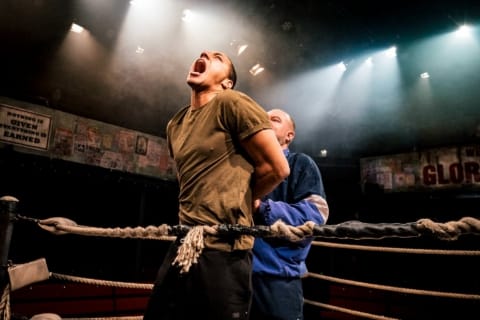 A coach holding a wrestler's hands tightly behind his back to hurt him
