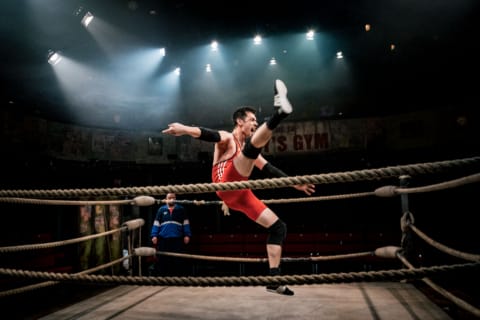 A wrestler in a ring kicking his foot high in the air
