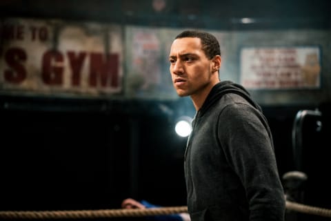 A wrestler in a hoodie looking across a gym
