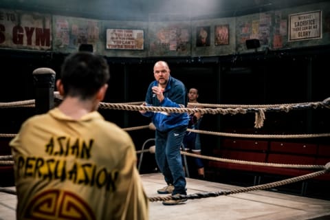a wrestling coach instructing a wrestler in a ring