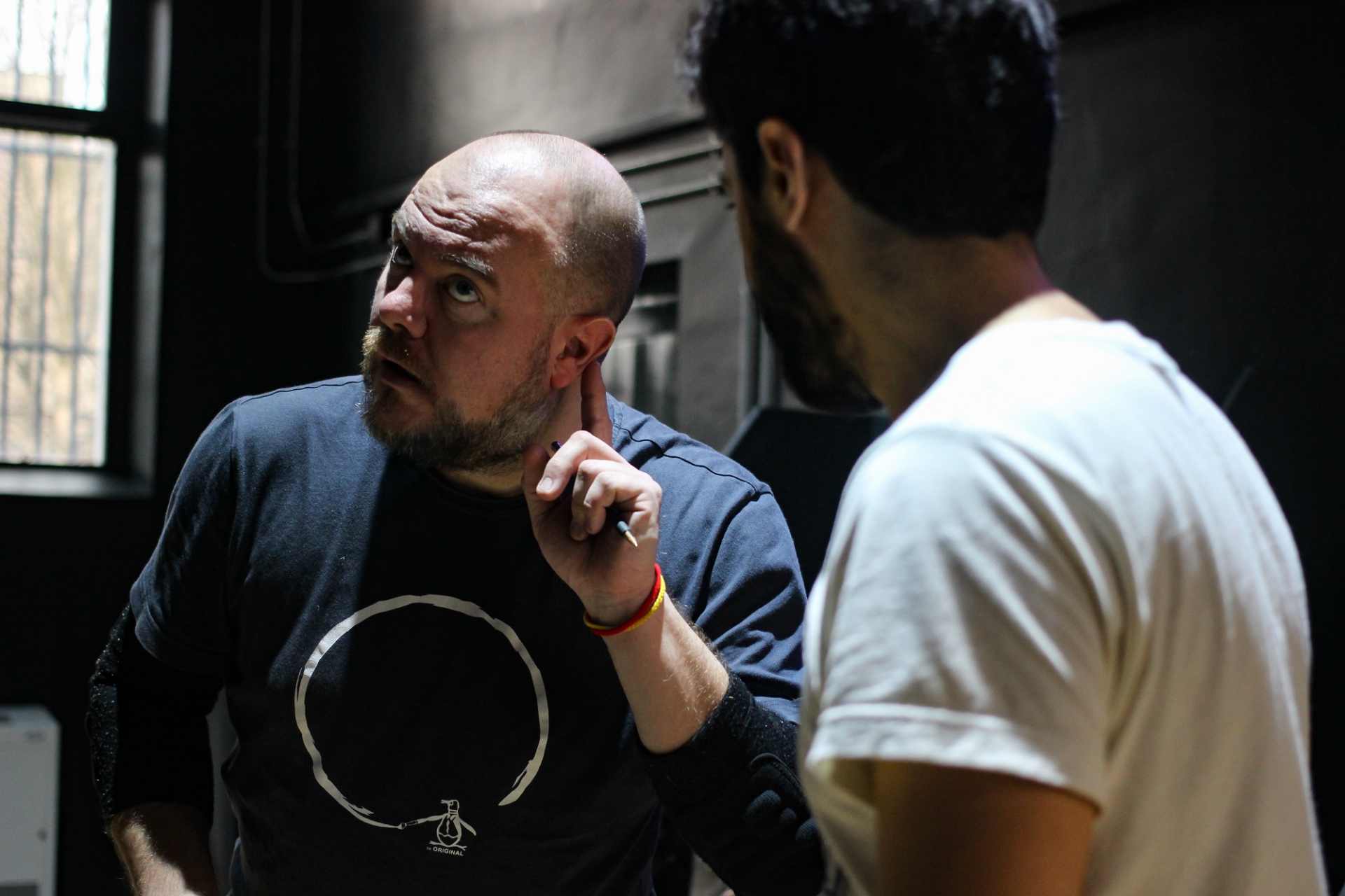 A wrestling coach holding his finger to his ear whilst talking to a wrestler
