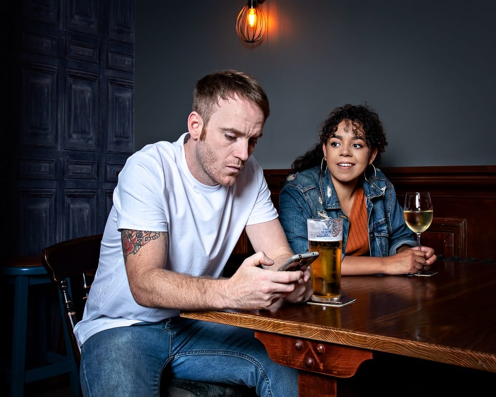 A man and a woman sat in a pub with drinks.