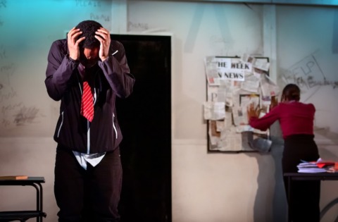 a teenage pupil covering his head as if blocking out sound as his teacher talks