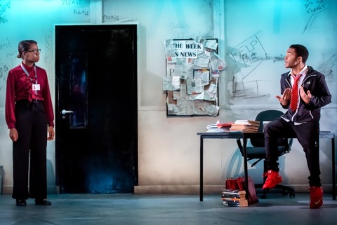 A teenage pupil and his teacher talking at a distance in the classroom