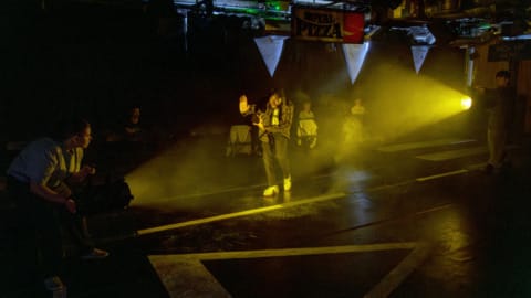 A taxi driver walking towards a bright light with his arms in front of him