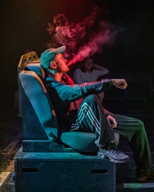 A man sat in the back of a taxi breathing out cigarette smoke calmly