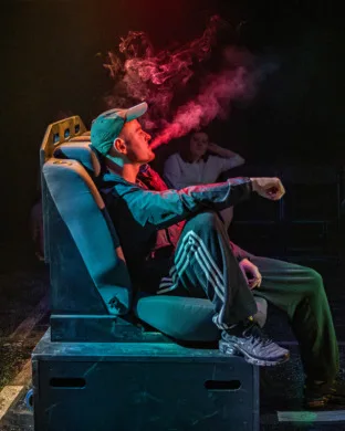 A man sat in the back of a taxi breathing out cigarette smoke calmly