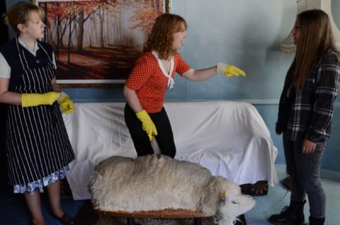 A woman pointing, with bright yellow washing up gloves on.