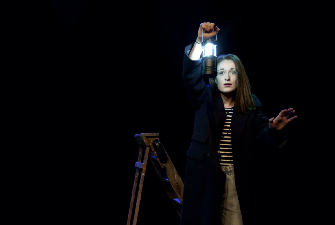 A woman holding up a lantern in the dark