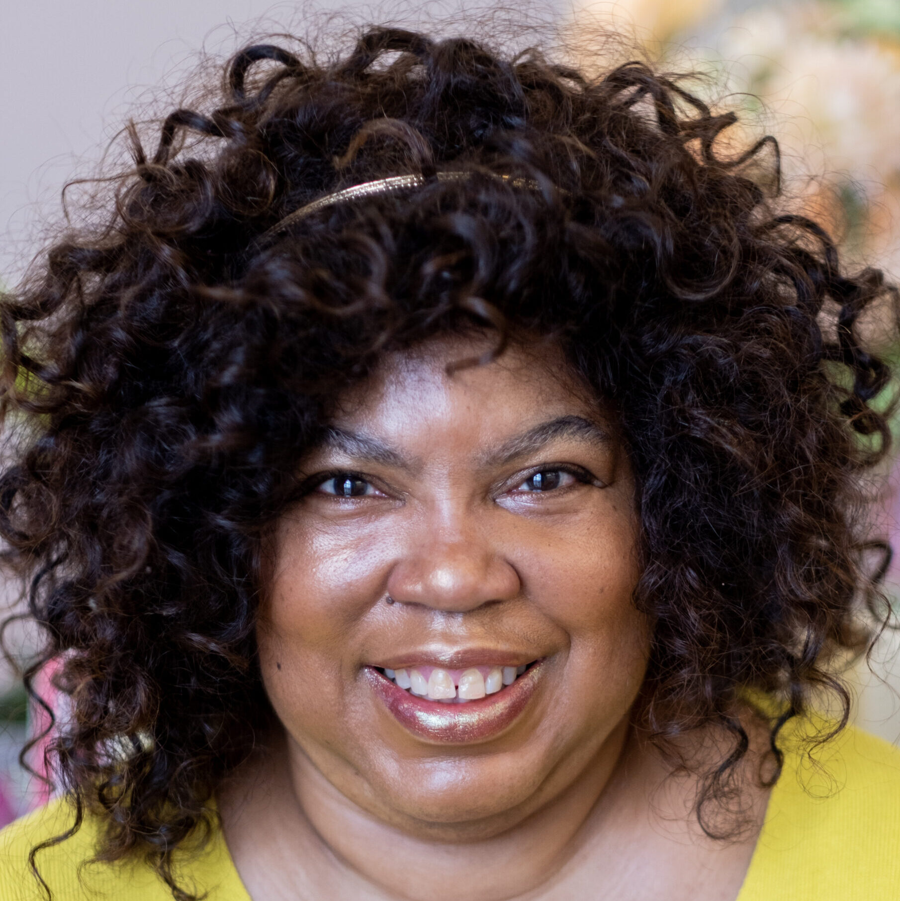A picture of Red Ladder Artistic Director Cheryl Martin smiling in a bright yellow v neck top