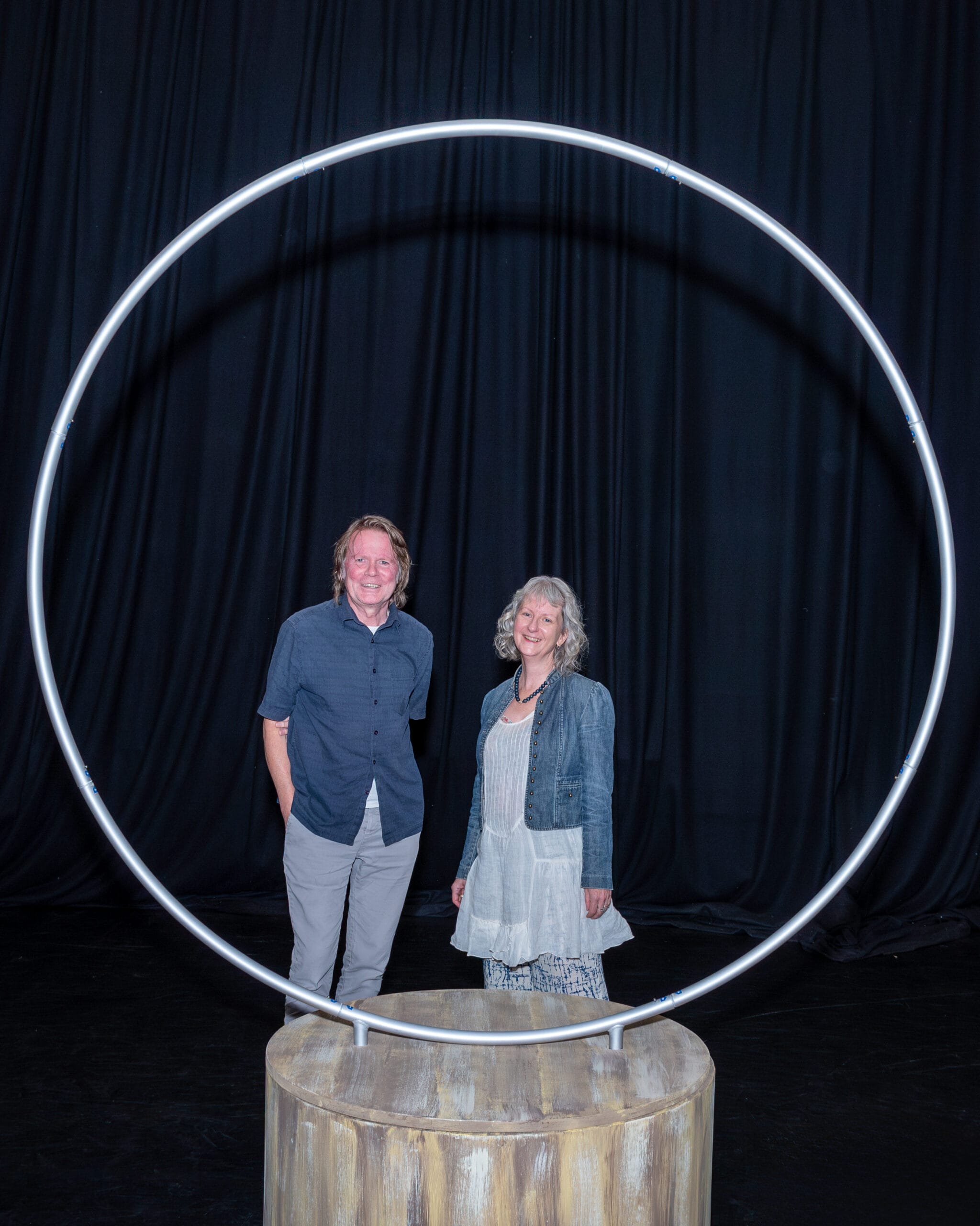 Playwrights Boff and Sarah stood behind a mounted circle from the Sanctuary set