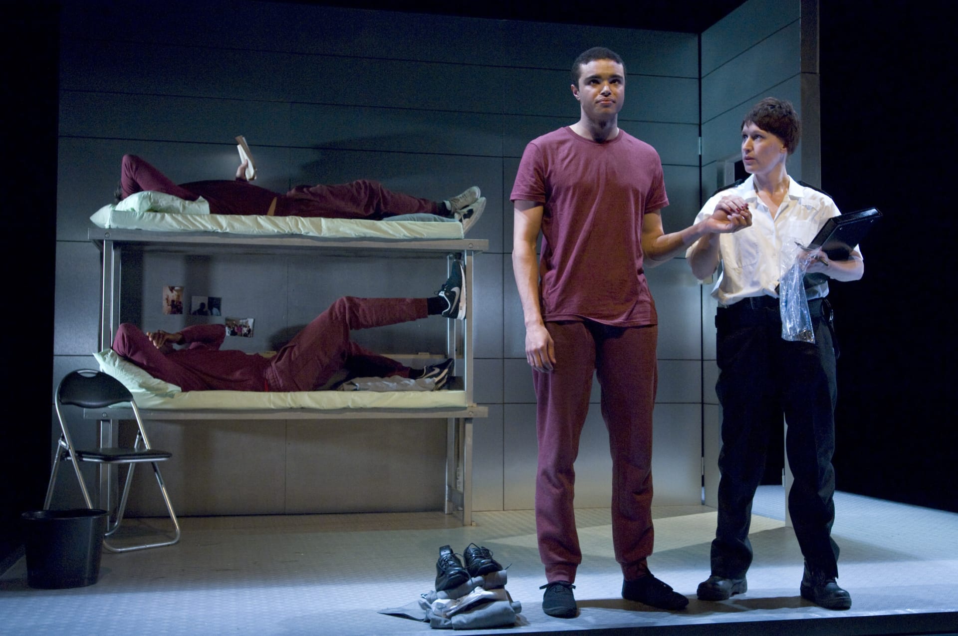 A prisoner touching the hand of an officer, while two other prisoners lie in their beds reading and lounging