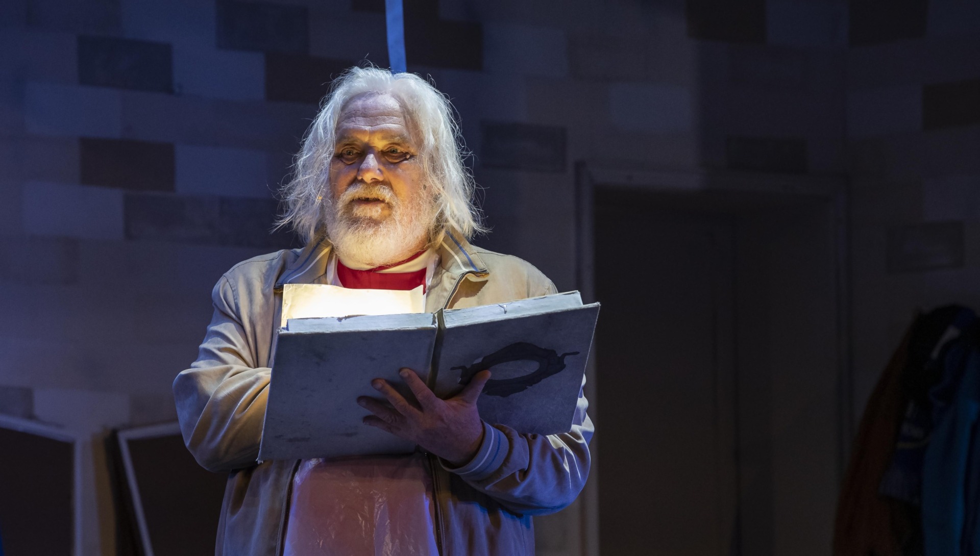 A man with long grey hair reading a large book