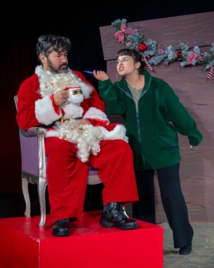 A woman threatening a grumpy santa with a christmas decoration to his throat
