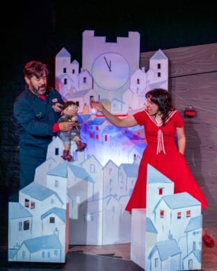 A man and woman making a puppet boy slide down a mountain
