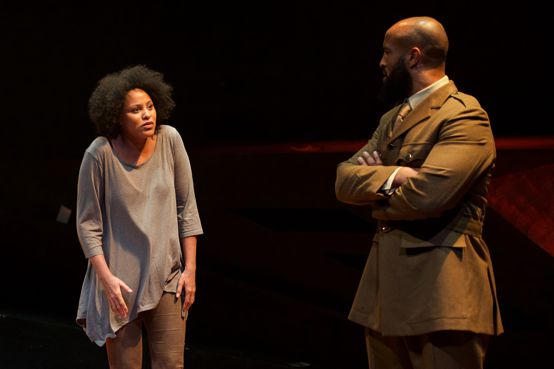 A woman cowering slightly whilst a soldier looks at her disapprovingly
