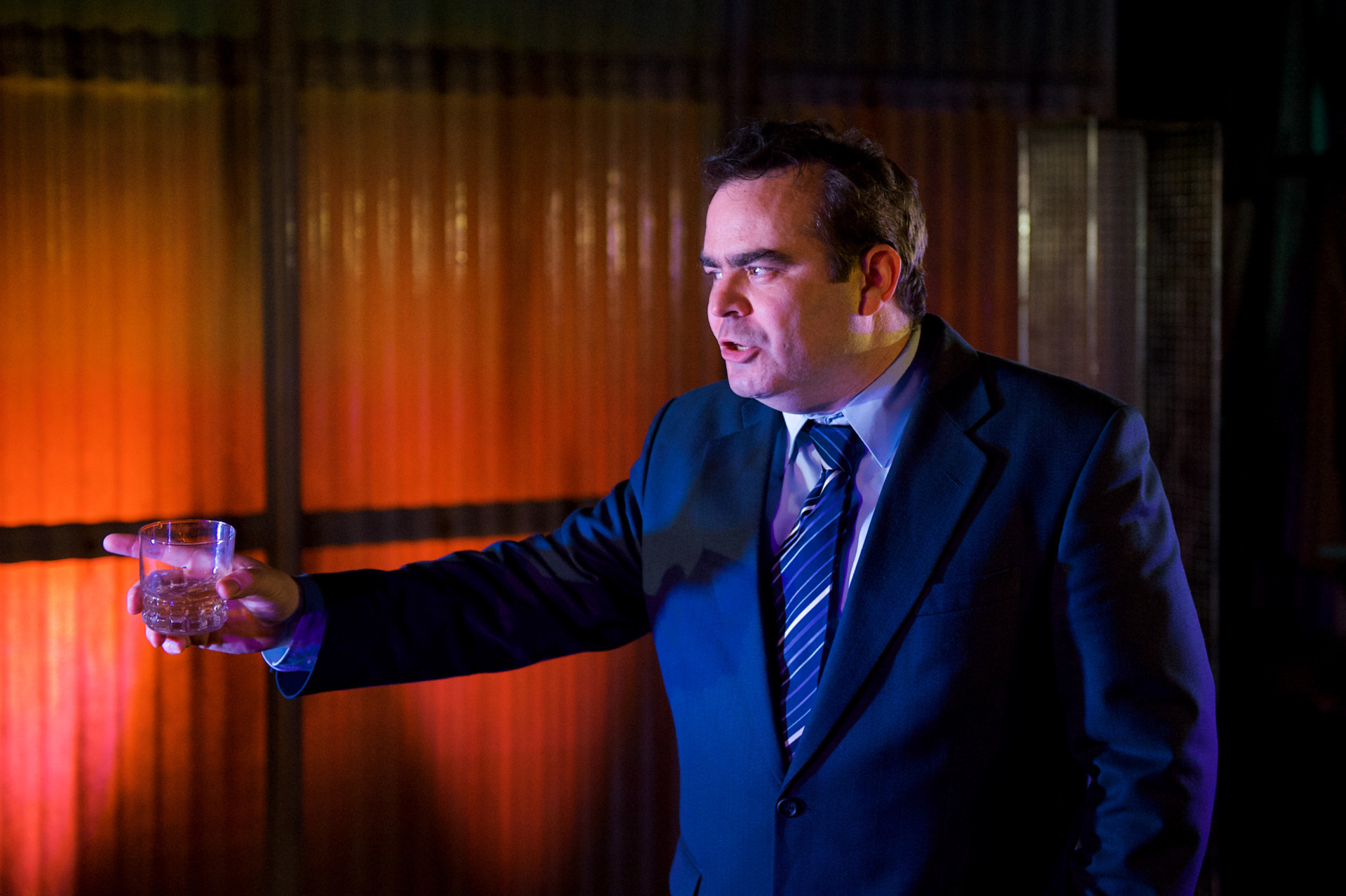 Football manager holding up a glass of whiskey mid-argument