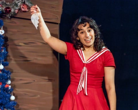 A girl in a red sailor dress holding up half a heart christmas decoration