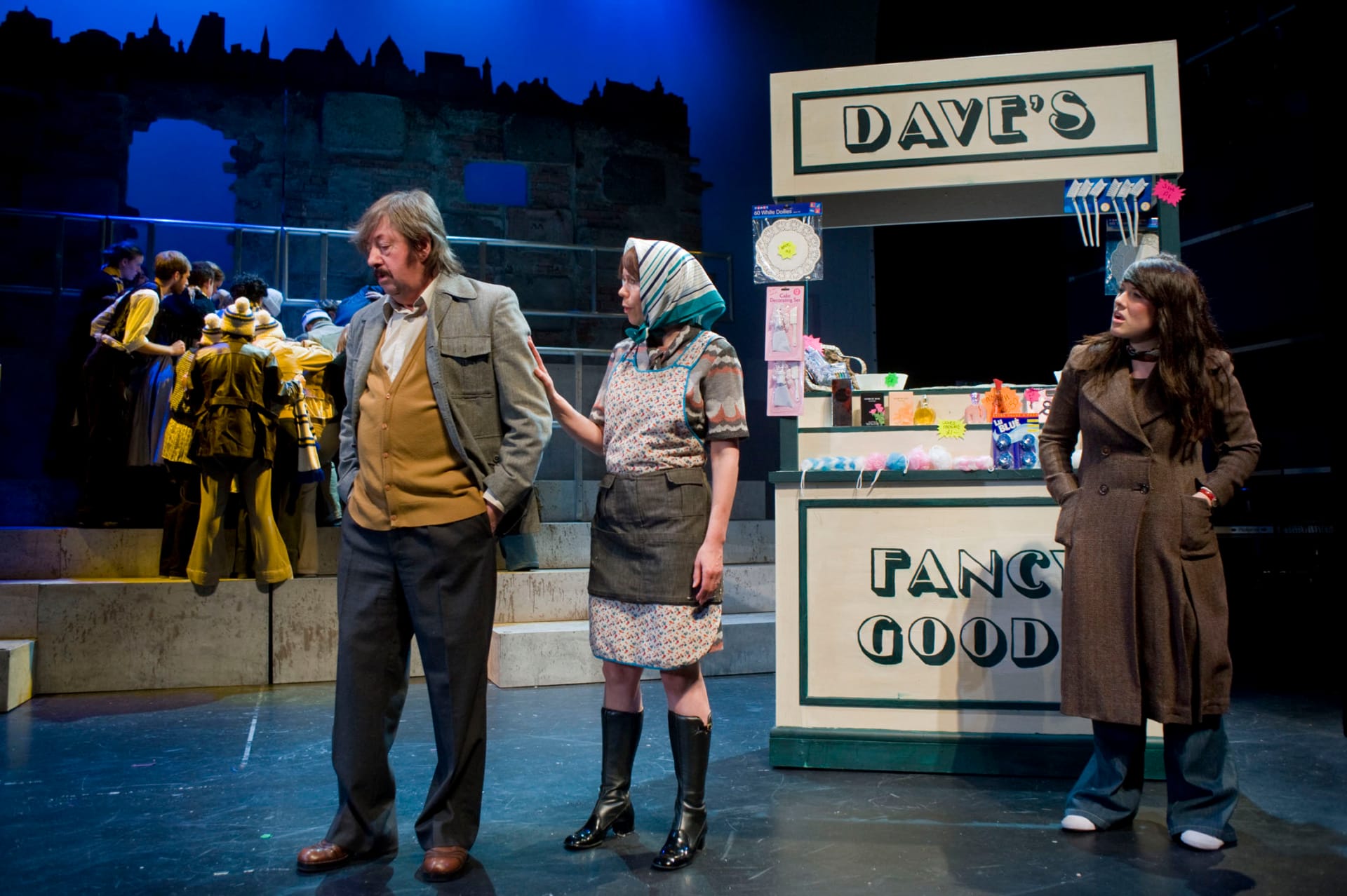 Three people speaking infront of a stand labelled 'Dave's Fancy Goods'