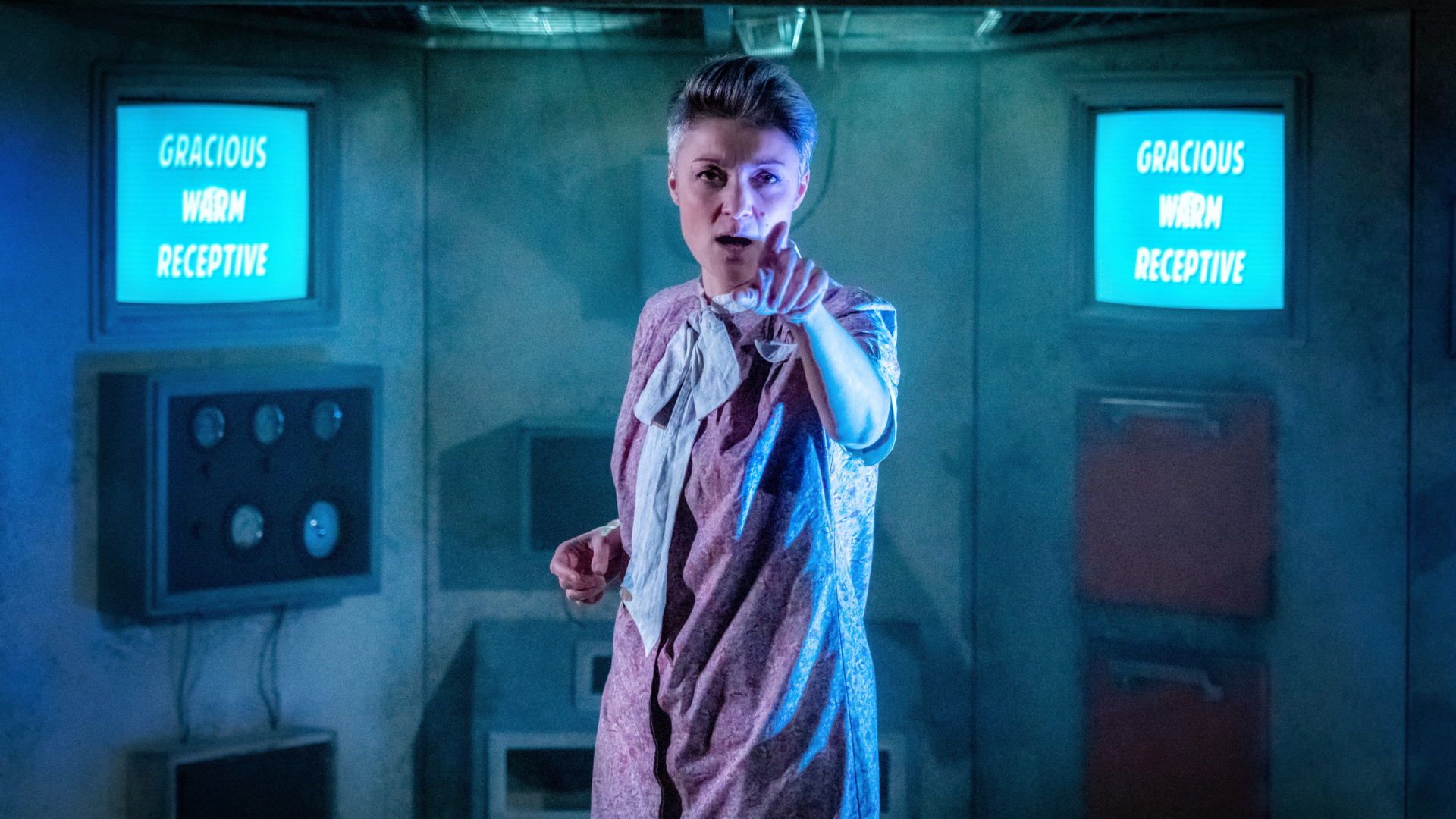A woman in a cell with screens pointing at the camera