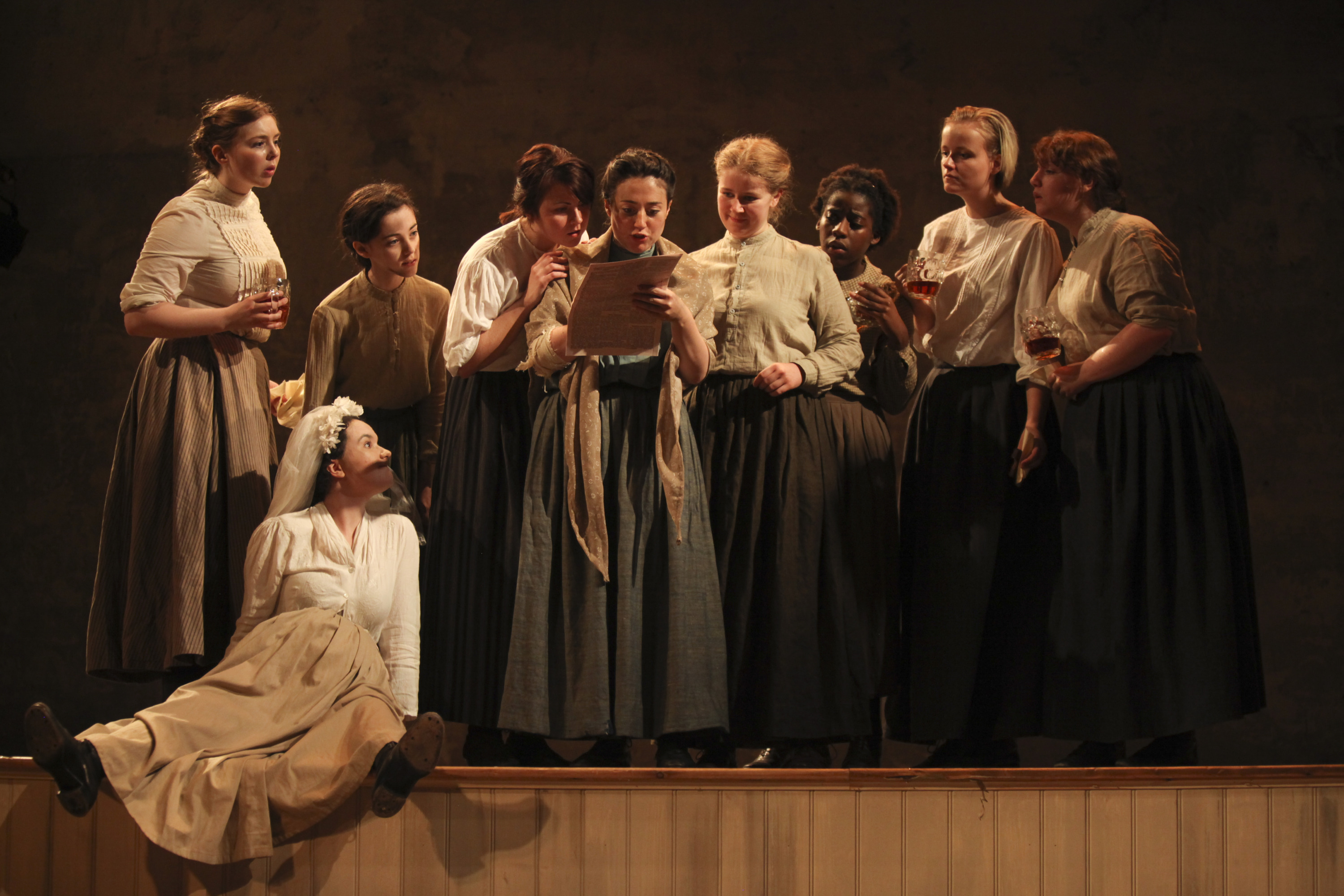 Victorian matchgirls gathered round a letter