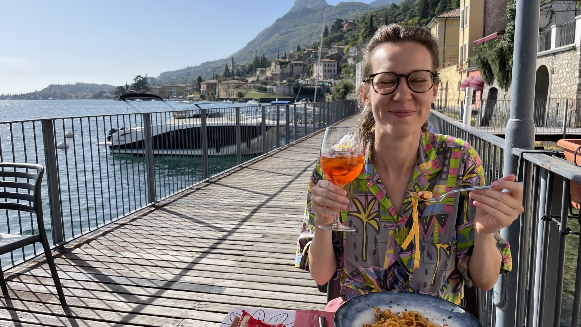 Alice sat at an outside table in Italy holding a glass of wine
