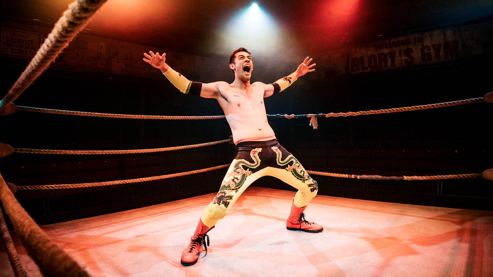 A wrestler in a ring with arms outstretched and mouth open shouting