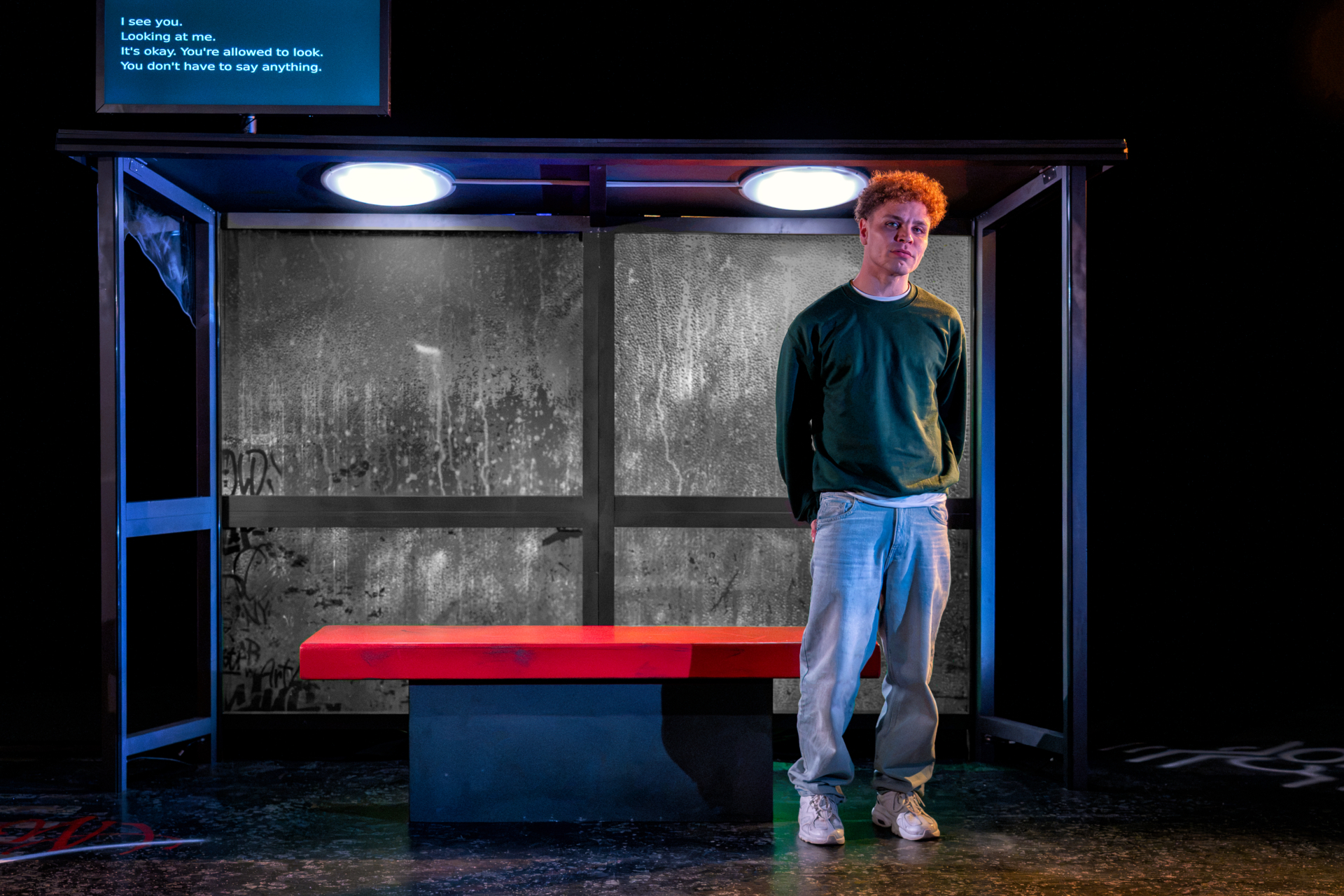 A young man stood at a bus stop staring into the lens