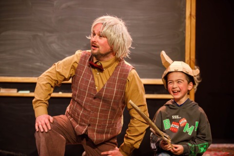 A man in a wig and waistcoat with a child in cardboard armour
