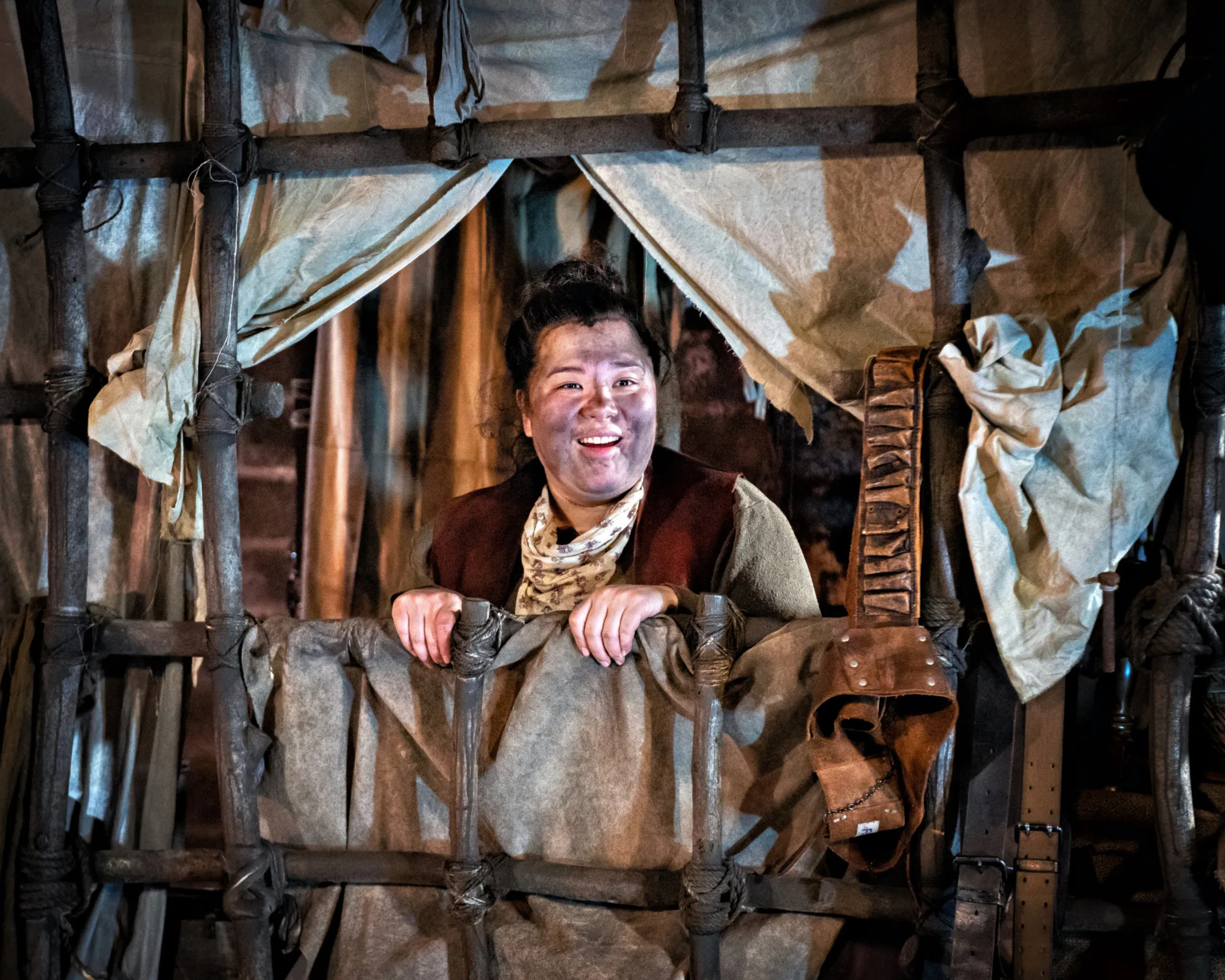 A woman in peasant's clothes looking through makeshift windown in a wooden cart