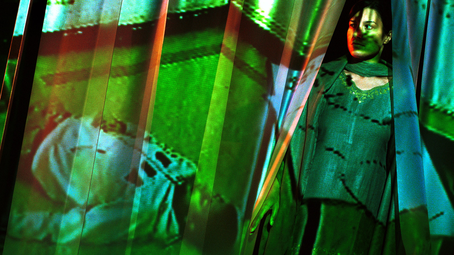 A mother coming through a curtain where a picture of her dead son is projected