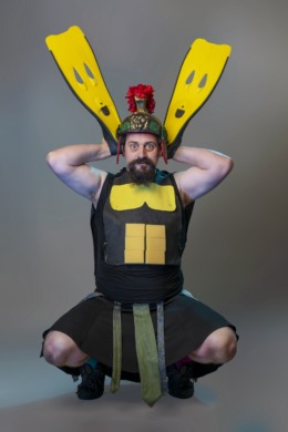 A gladiator with paper abs stuck on holding flippers behind his head.