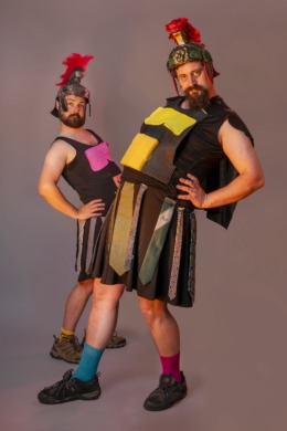 Two gladiators with paper abs stuck on striking a silly pose with hands on hips