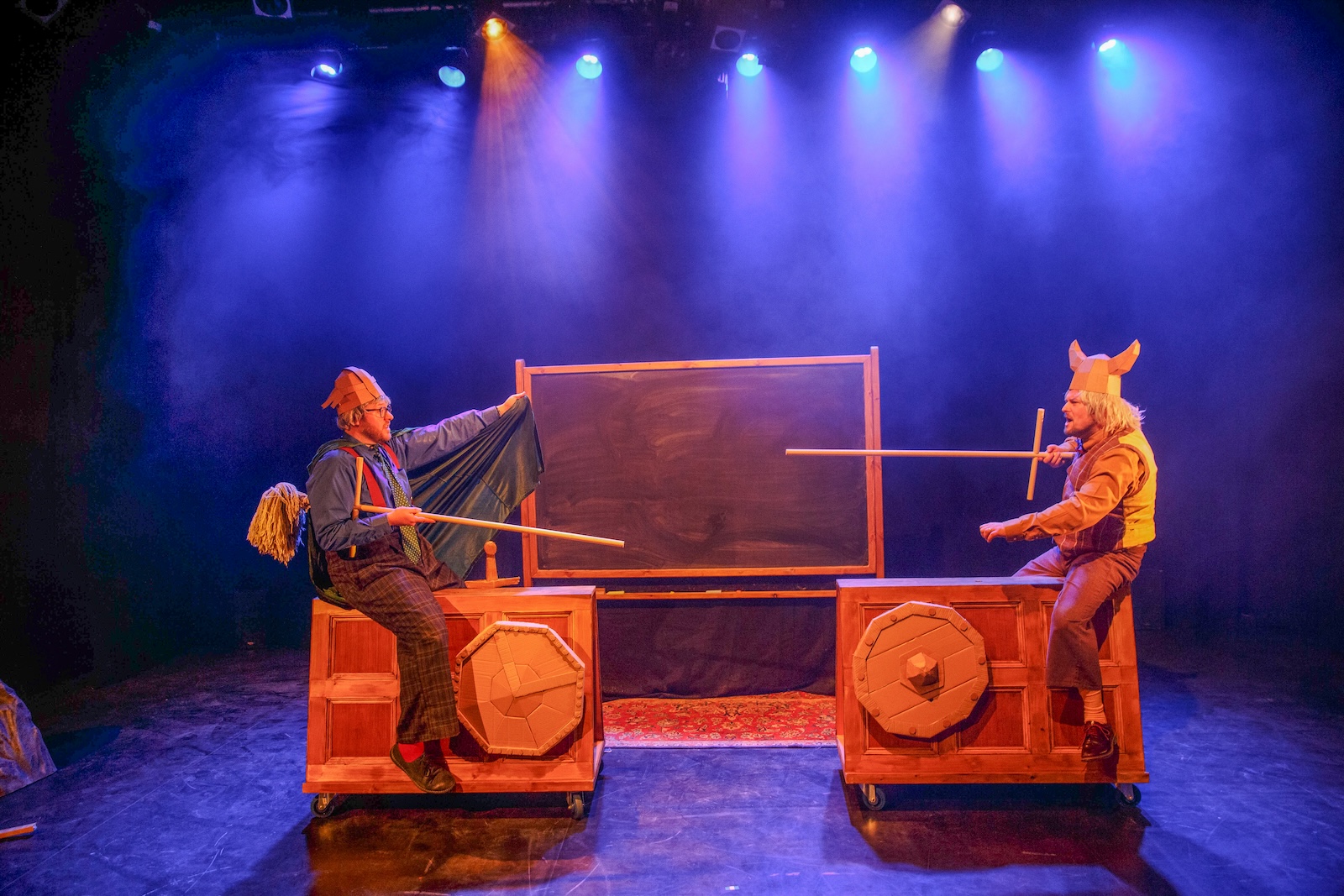 Two men jousting on cardboard stands with cardboard armour