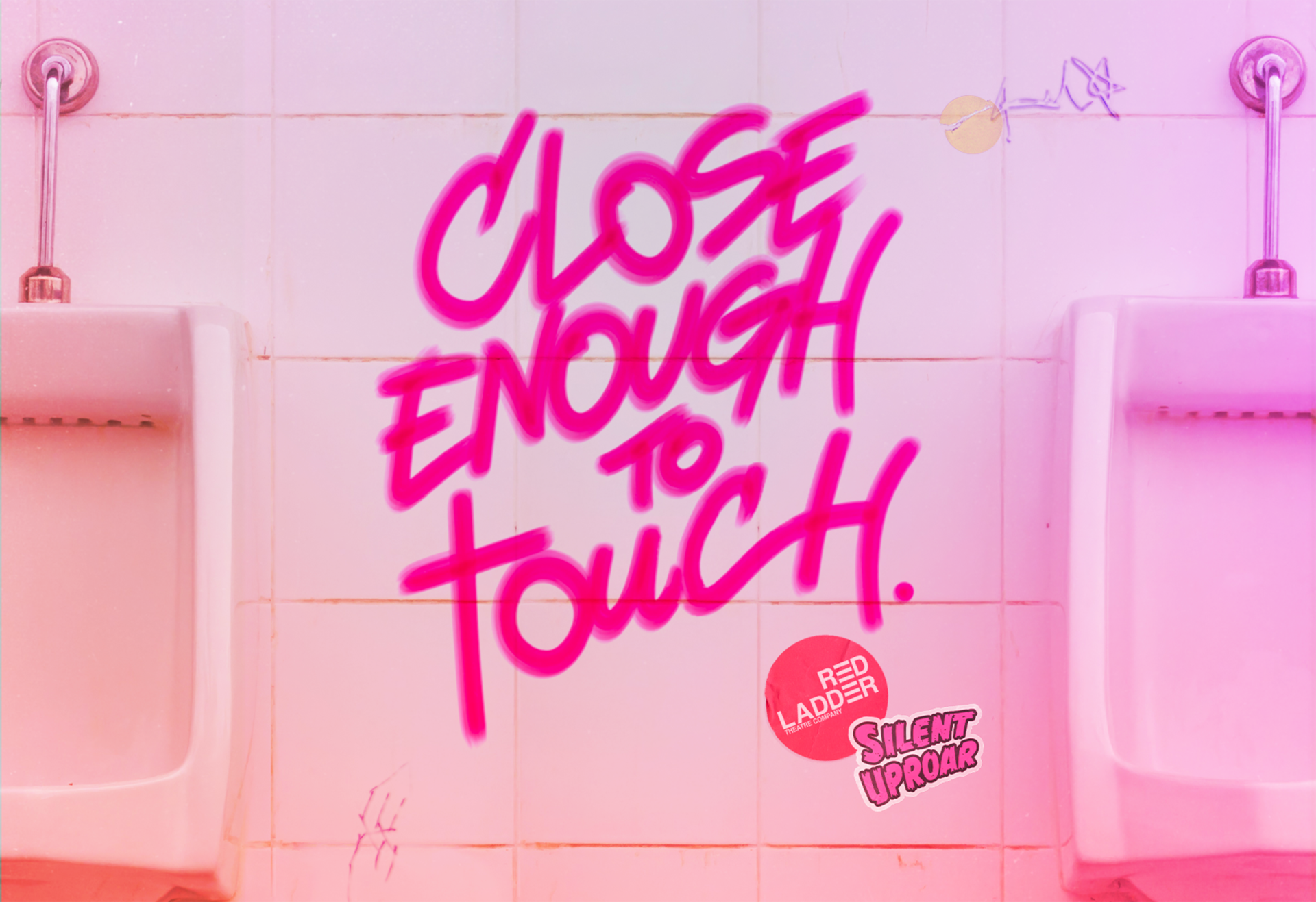 A graffiti title saying 'close enough to touch' in pink marker pen sits on the white tiles of a public toilet between two urinals