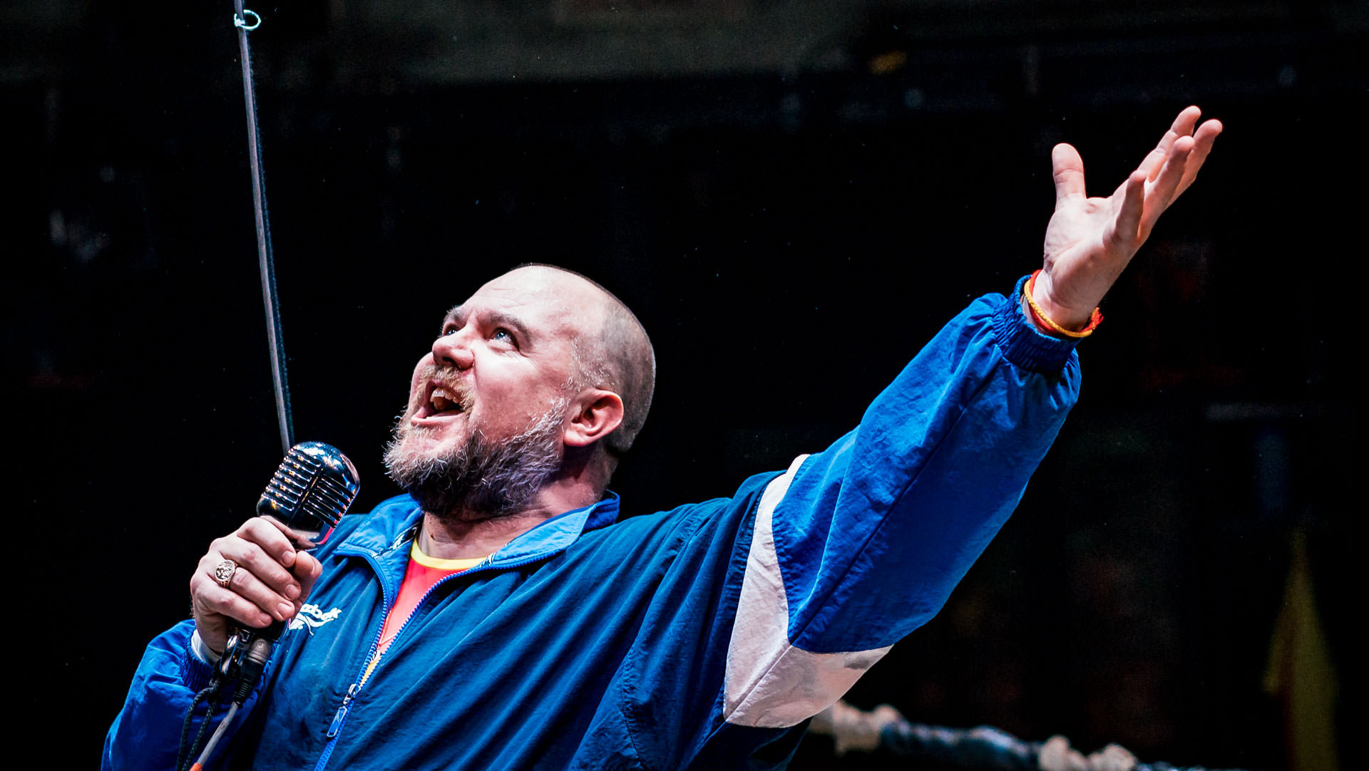 A wrestling coach announcing into a microphone in a ring