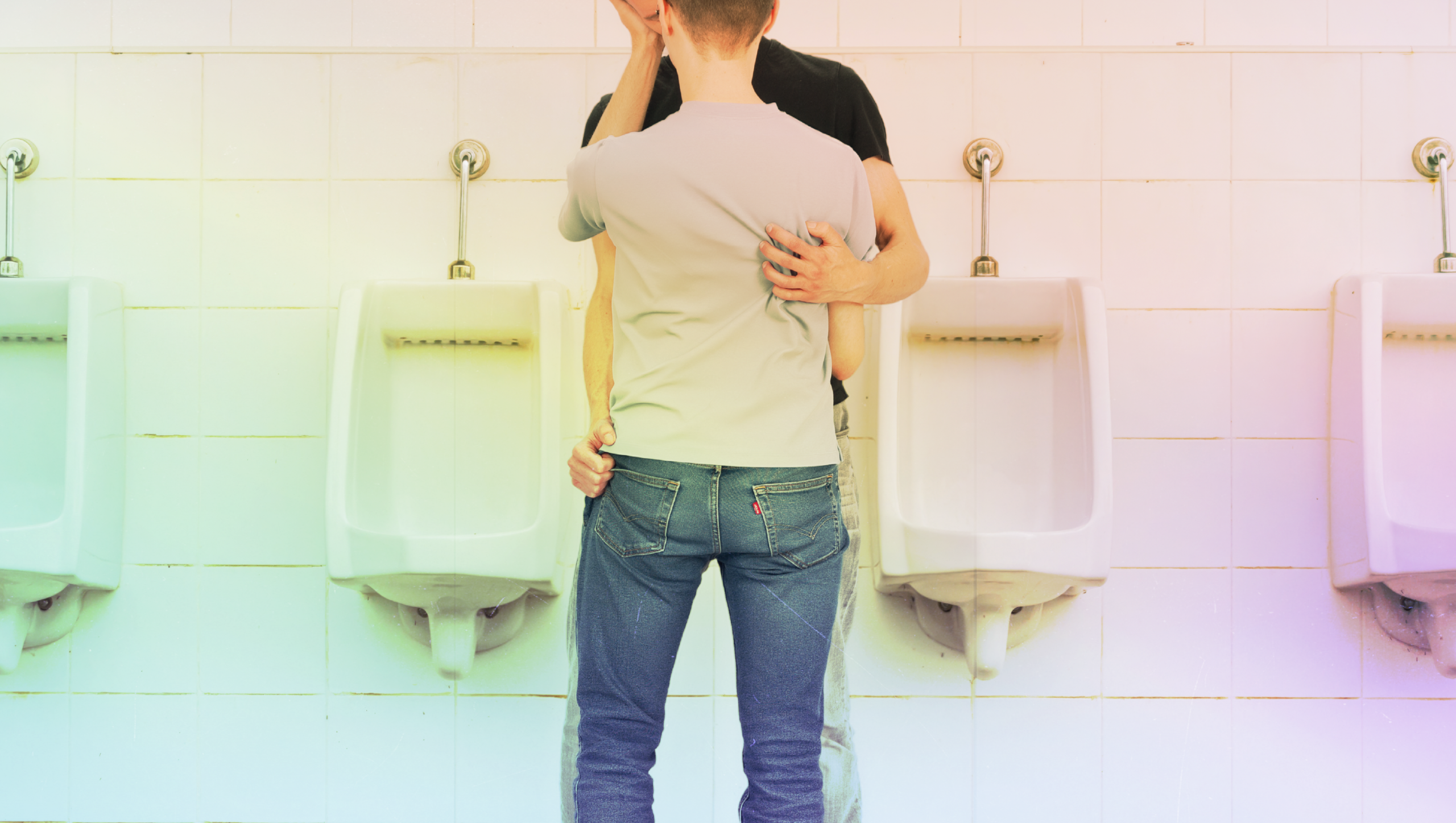 Two men in a passionate embrace in a men's urinal