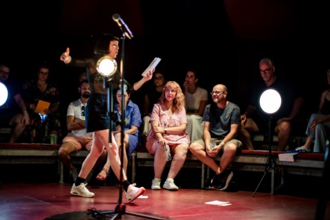 A woman reading from a piece of paper to an audience