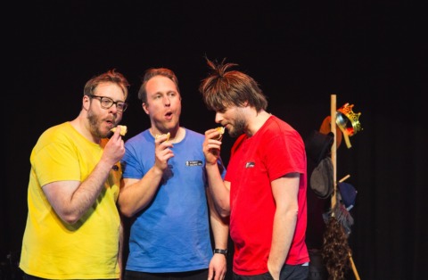 Three men eating sausage rolls