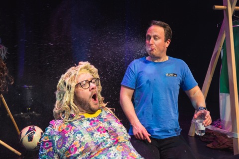 A man spitting water in surpise across another