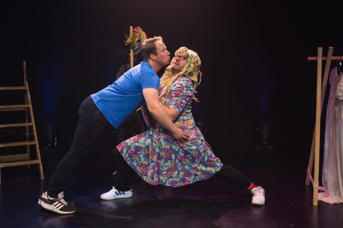 A man trying to kiss another man in drag who is reluctant