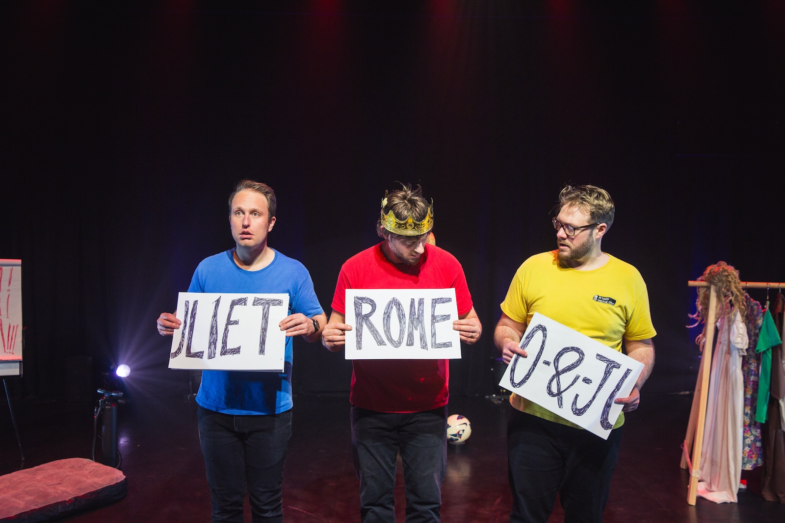 Three men holding up signs reading Romeo and Juliet in the wrong order