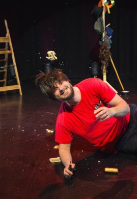 a man on the floor chomping on a sausage roll