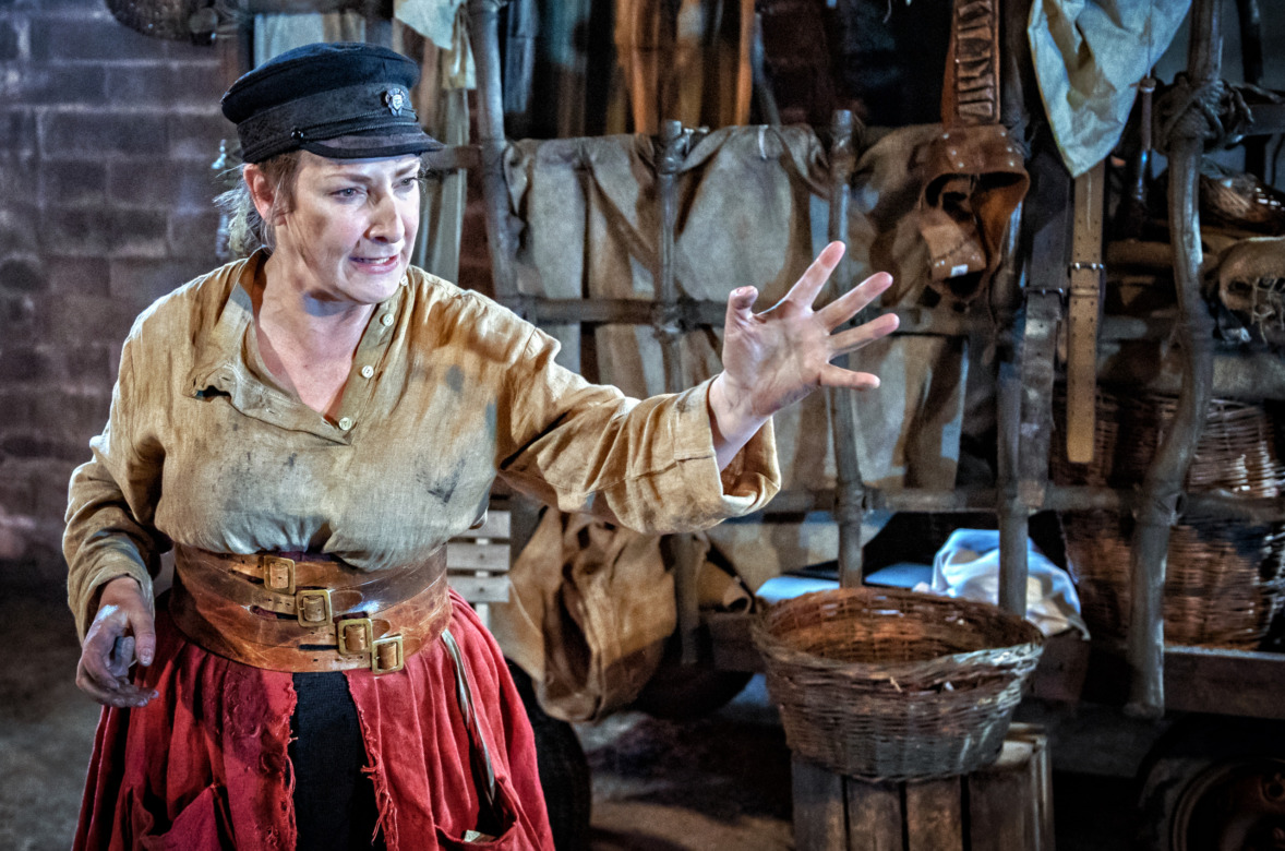 A woman in peasant clothes talking with her hand outstretched for emphasis