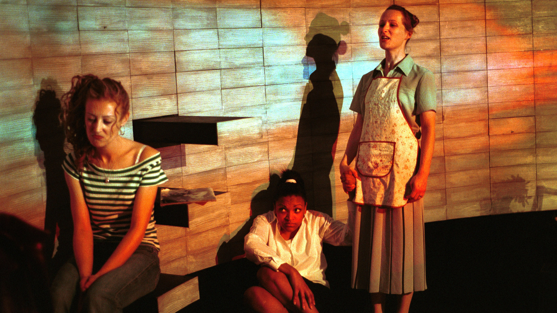 Three women on stage with a projection over them