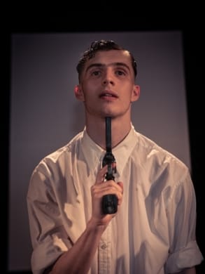 A young man holding a gun to his throat