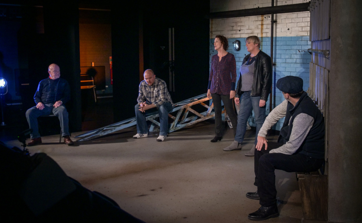 Five people in silence in a locker room